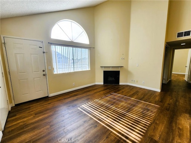 foyer entrance featuring high vaulted ceiling, dark hardwood / wood-style floors, and a textured ceiling