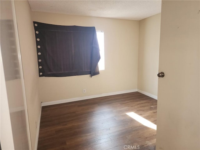 unfurnished room with dark wood-type flooring and a textured ceiling