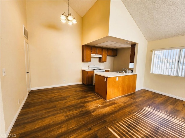 kitchen featuring kitchen peninsula, a notable chandelier, dark wood-type flooring, white gas stove, and sink