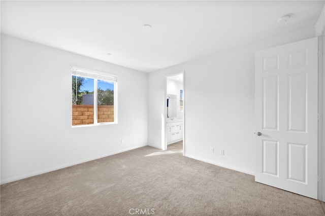 unfurnished bedroom with baseboards, ensuite bath, and carpet flooring