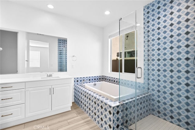 full bathroom featuring a shower stall, a garden tub, a wealth of natural light, wood finished floors, and vanity