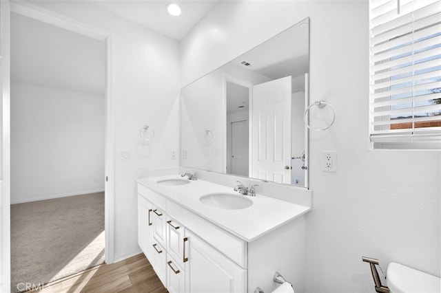 full bath with a sink, baseboards, wood finished floors, and double vanity