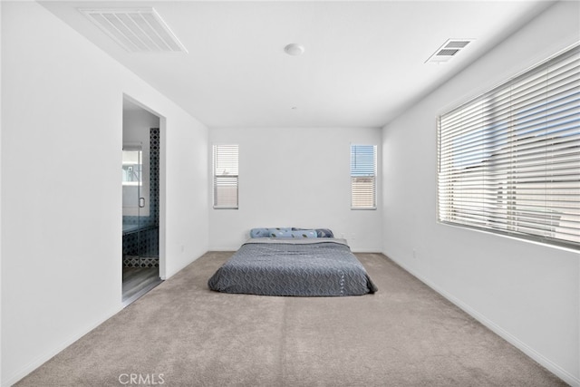 carpeted bedroom featuring visible vents and ensuite bath