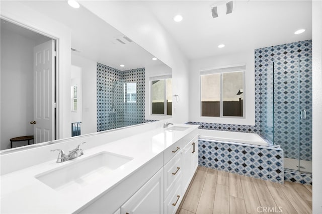 full bathroom with double vanity, a stall shower, wood tiled floor, and a sink