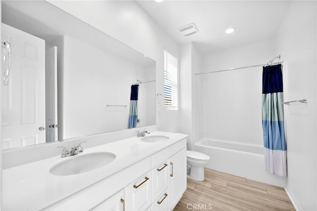 full bathroom featuring visible vents, toilet, wood finished floors, and a sink