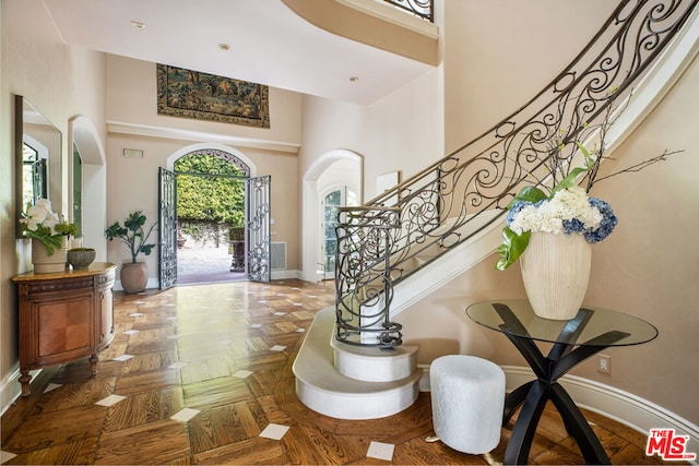 foyer with a towering ceiling and parquet floors