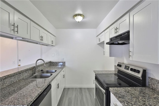 kitchen featuring appliances with stainless steel finishes, dark stone countertops, white cabinets, and sink