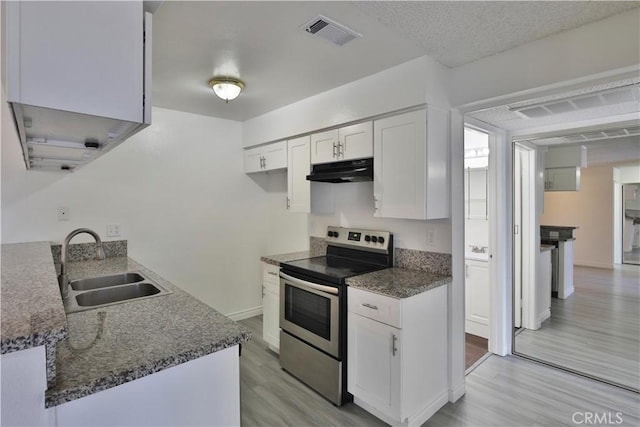 kitchen featuring sink, white cabinetry, light wood-type flooring, stainless steel range with electric stovetop, and dark stone counters