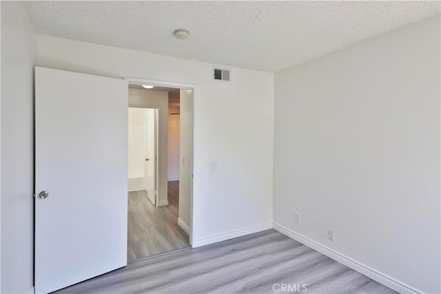 spare room featuring a textured ceiling and light wood-type flooring