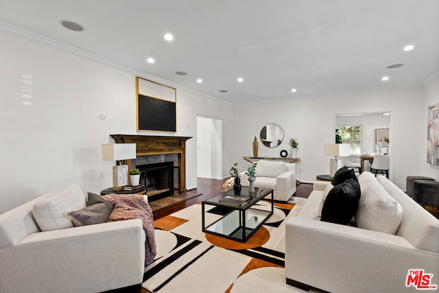 living room featuring crown molding, light hardwood / wood-style floors, and a tiled fireplace