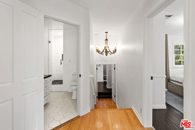 bathroom featuring hardwood / wood-style flooring, toilet, and an inviting chandelier