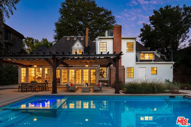 back house at dusk featuring a pergola, a patio area, and outdoor lounge area