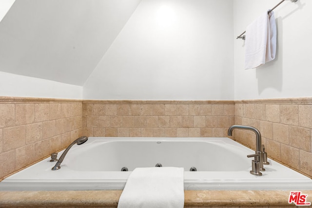 bathroom featuring a tub to relax in and vaulted ceiling