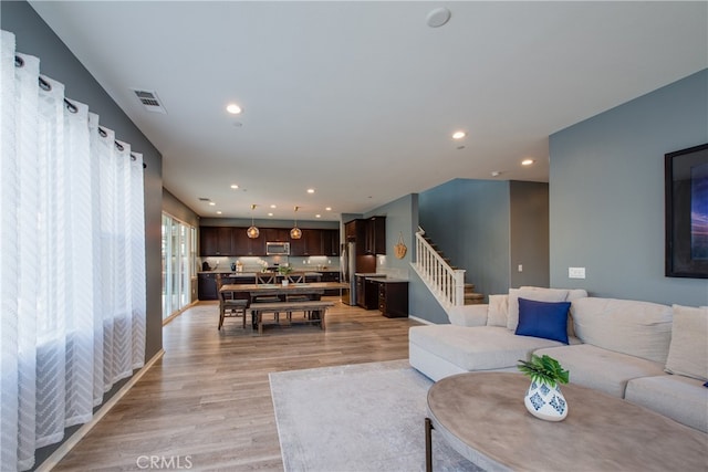 living area featuring stairs, visible vents, light wood-style flooring, and recessed lighting