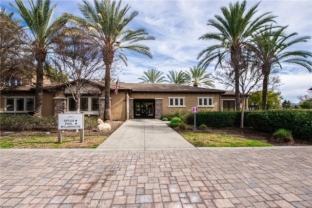 view of front of house featuring stone siding, driveway, and stucco siding