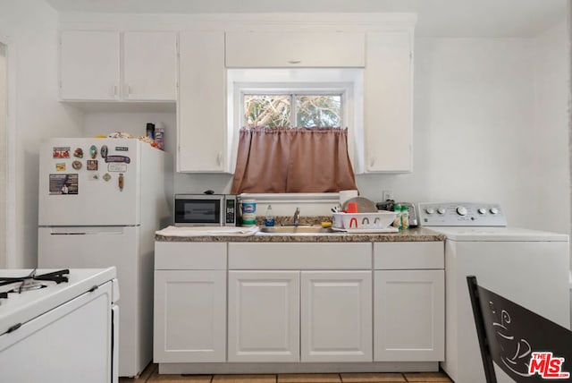 kitchen with washer / dryer, white fridge, sink, light tile patterned floors, and white cabinets