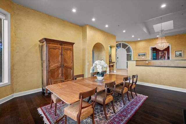 dining space featuring dark hardwood / wood-style flooring, a chandelier, and a raised ceiling