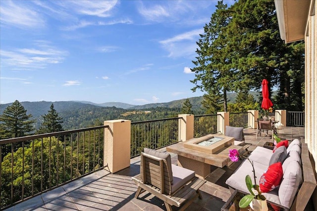 wooden deck featuring a mountain view and an outdoor living space with a fire pit