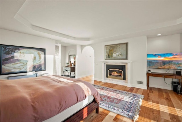 bedroom with a raised ceiling and light hardwood / wood-style floors