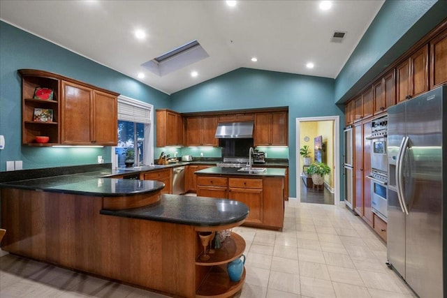 kitchen featuring light tile patterned floors, stainless steel appliances, an island with sink, vaulted ceiling, and kitchen peninsula