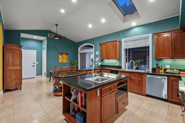 kitchen featuring stainless steel appliances, lofted ceiling with skylight, sink, and a center island with sink