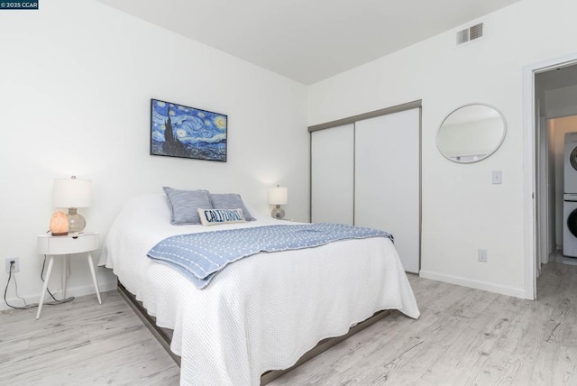 bedroom featuring stacked washing maching and dryer, a closet, and light hardwood / wood-style floors