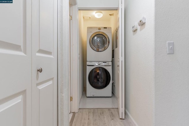 washroom with light hardwood / wood-style floors and stacked washer and dryer