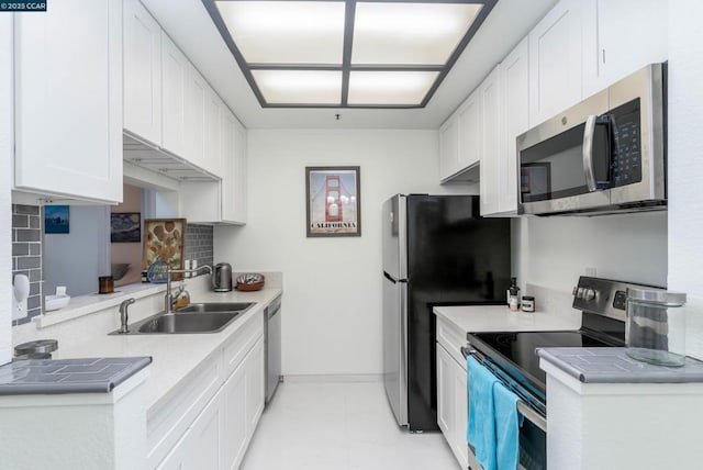 kitchen featuring white cabinets, backsplash, appliances with stainless steel finishes, and sink