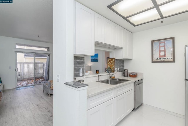 kitchen with tasteful backsplash, sink, stainless steel dishwasher, and white cabinetry