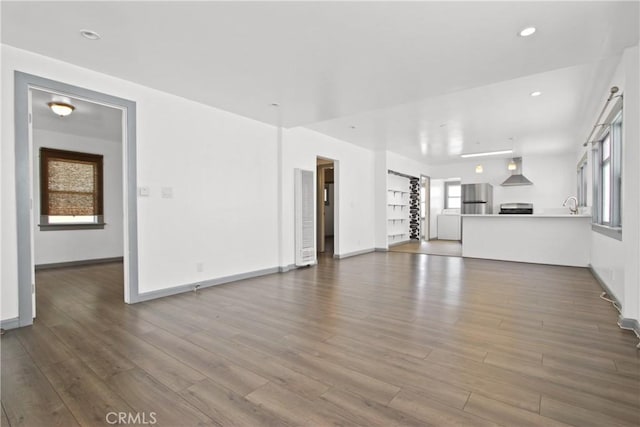 unfurnished living room with wood finished floors, baseboards, and recessed lighting