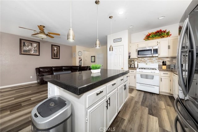 kitchen featuring decorative light fixtures, white cabinetry, a center island, decorative backsplash, and appliances with stainless steel finishes