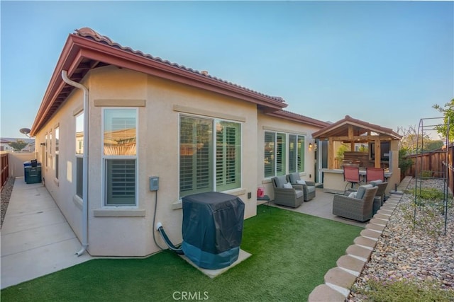 rear view of property featuring a patio area, a yard, and an outdoor hangout area