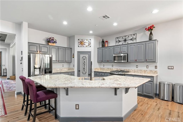 kitchen with a breakfast bar, a kitchen island with sink, appliances with stainless steel finishes, and sink