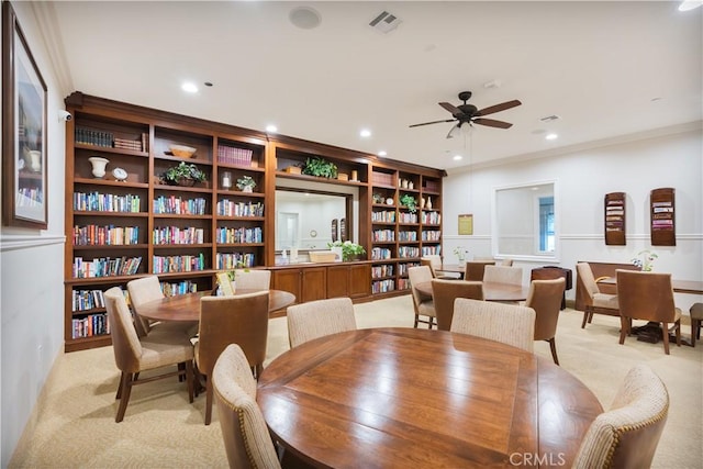 carpeted dining room featuring ceiling fan and ornamental molding