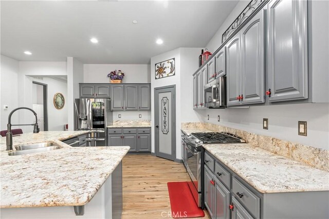 kitchen featuring light stone counters, sink, gray cabinets, and stainless steel appliances