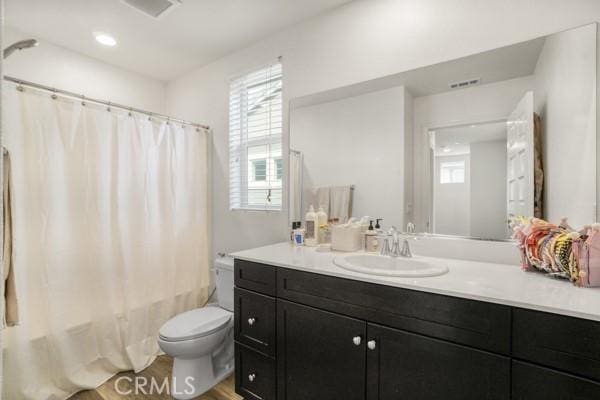 full bathroom featuring hardwood / wood-style flooring, toilet, vanity, and shower / tub combo