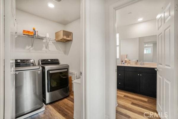 laundry area with sink, washing machine and dryer, and light wood-type flooring