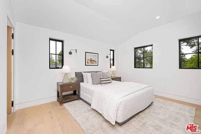 bedroom with lofted ceiling, wood-type flooring, and multiple windows