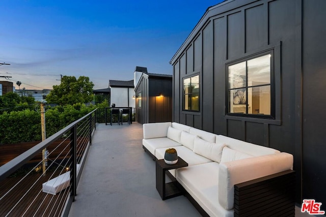 patio terrace at dusk featuring a balcony and an outdoor living space