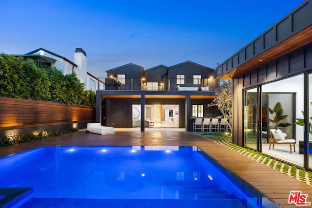 pool at dusk featuring a deck