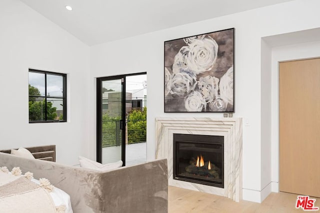 bedroom featuring light wood-type flooring, access to exterior, a premium fireplace, and lofted ceiling