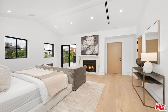 bedroom featuring light hardwood / wood-style flooring and vaulted ceiling with beams