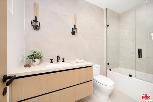 full bathroom featuring tile walls, toilet, vanity, and shower / bath combination with glass door