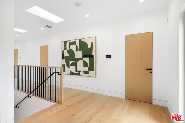 hallway featuring a skylight and hardwood / wood-style flooring