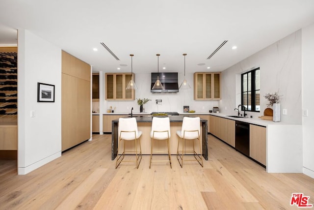 kitchen with dishwasher, a center island, sink, light wood-type flooring, and a breakfast bar area