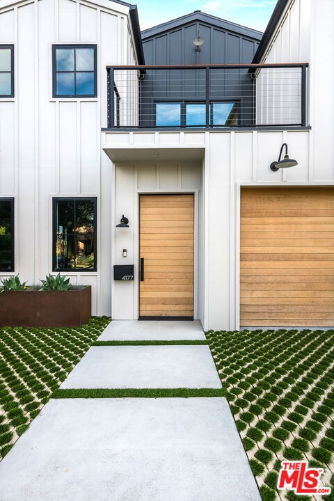 entrance to property with a balcony, a garage, and a yard