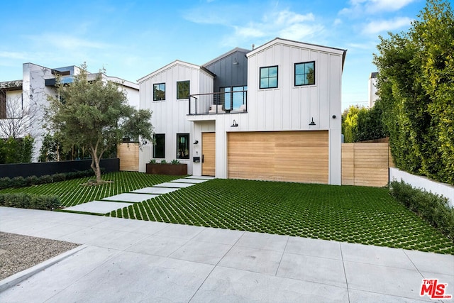 view of front of house featuring a garage, a front yard, and a balcony