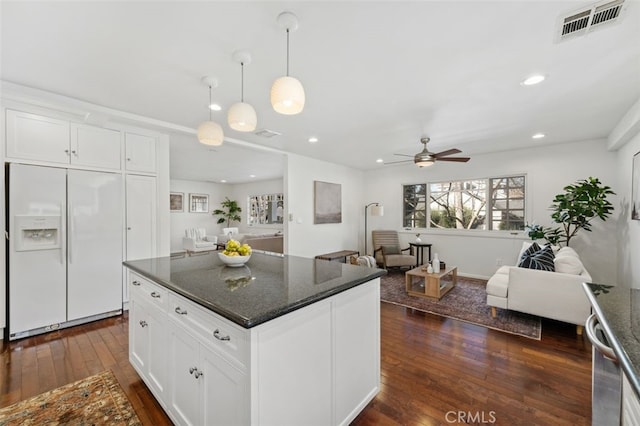 kitchen with white cabinetry, dark stone counters, white refrigerator with ice dispenser, and pendant lighting