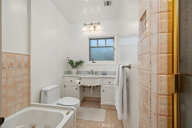 bathroom with sink, tile walls, tile patterned flooring, a tub, and toilet