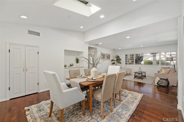 dining space featuring dark hardwood / wood-style flooring and a skylight